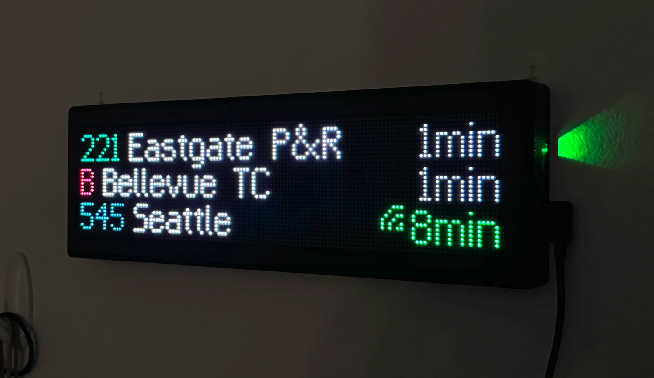 A matrix display placed in the final 3D-printed frame and mounted on the wall, showing three departures from public transit routes.