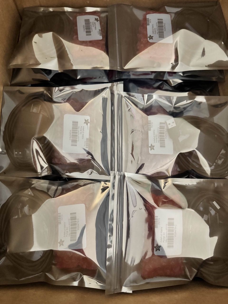 Several shiny silver anti-static bags with power supplies, cords, and electrical components inside.