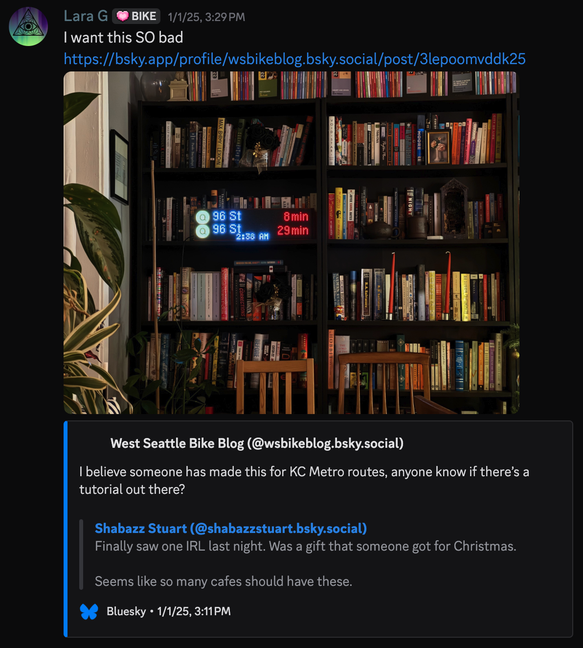 Discord message from Lara G on January 1, 2025 at 3:29 PM which says "I want this SO bad". An image of an LED matrix display showing departure times for the next two Q trains to 96th St. The display is on a bookshelf with many, many books.
